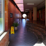 Alcino Soutinho's Department of Ceramics and Glass Engineering at the University of Aveiro showcasing a clean, daylight-filled lobby with composite material flooring, wood-stained ceiling, and tiled surfaces.