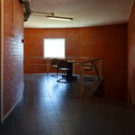 Alcino Soutinho's Department of Ceramics and Glass Engineering at the University of Aveiro showcasing an interior with brickwork walls, wood-stained flooring, and metal ceiling elements.