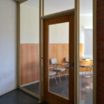 Alcino Soutinho's Department of Ceramics and Glass Engineering at the University of Aveiro showcasing an interior with hardwood flooring, expansive glass walls, and a modern ceiling design.