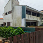 Alcino Soutinho’s Habitação unifamiliar em Matosinhos showcasing a residential building with concrete and plaster materials, featuring balconies and designed for optimal daylighting and shade within an urban setting.