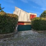 Alcino Soutinho's Habitação unifamiliar em Ofir showcasing a modern residential design with a landscaped garden, shaded driveway, and coniferous hedges.