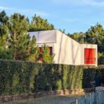 Alcino Soutinho's Habitação unifamiliar em Ofir showcasing a modern design with a lush garden, manicured lawn, and surrounding landscaping elements.