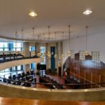 Alcino Soutinho's Matosinhos Town Hall showcasing a modern interior design with varnished flooring, contemporary furniture, strategic lighting, and expansive glass elements in the hall.