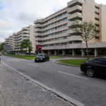 Alcino Soutinho’s Quinta das Sedas, a high-rise condominium and commercial building showcasing brutalist architecture with exposed concrete surfaces, integrated parking areas, and surrounding city and family cars.