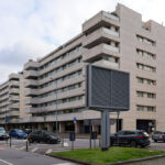 Alcino Soutinho’s Quinta das Sedas showcasing a modern condominium complex with a sleek glass façade, multiple apartment units, and integrated public spaces in an urban metropolitan area during daytime.