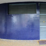 Alcino Soutinho’s Quinta das Sedas showcasing a modern composite material façade with concrete and tile elements, large glass windows enhancing daylighting, and dynamic shadow patterns.