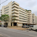 Alcino Soutinho’s Quinta das Sedas, a mixed-use high-rise building in a metropolitan area, showcasing a concrete and composite material façade with modern urban design elements and integrated commercial and residential apartments.