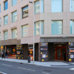 Alcino Soutinho’s design of Sede Norte do BPI showcasing a modern commercial headquarters with a composite material façade and sleek geometric forms in a metropolitan area.