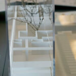 Inês Lobo’s 18 Architectural Townhouses, Lot 126, showcasing a silver composite material façade with extensive glass transparency, sharp geometric design, and dynamic shadow play.