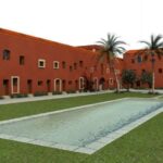 Eduardo Souto de Moura’s Convento das Bernardas Residence showcasing a historic hacienda-style courtyard with palm trees and modern campus elements.