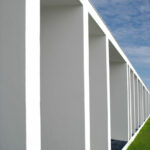 Nuno Graça Moura’s 30 Architectural "Bar Code 1" Townhouses, Lot 152, showcasing symmetrical concrete and composite material façades with artificial turf lawns and dynamic daylighting casting shadows.