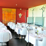 Nuno Graça Moura’s Tennis Club, Lot 161 interior showcasing modern furniture with chairs and tables set with linens, barware, and stemware in a stylish restaurant setting.